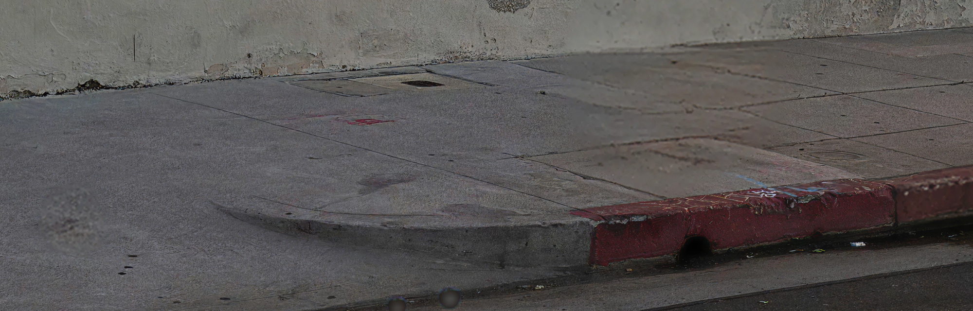 A concrete curb cut sloping from the pavement down to the road, its kerb edge painted red.