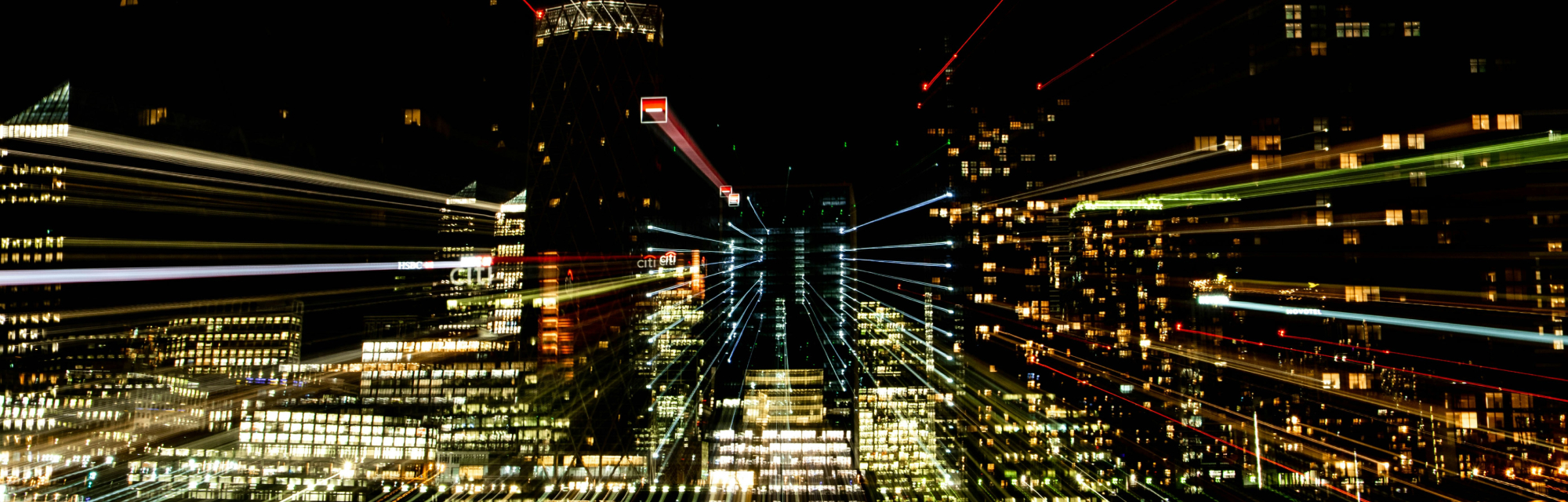 A night-time financial-district skyline with a zoom-burst effect, streaks of light radiating outward from the illuminated towers.